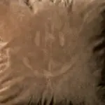 Smiley face impression in a velvet pillow surface.